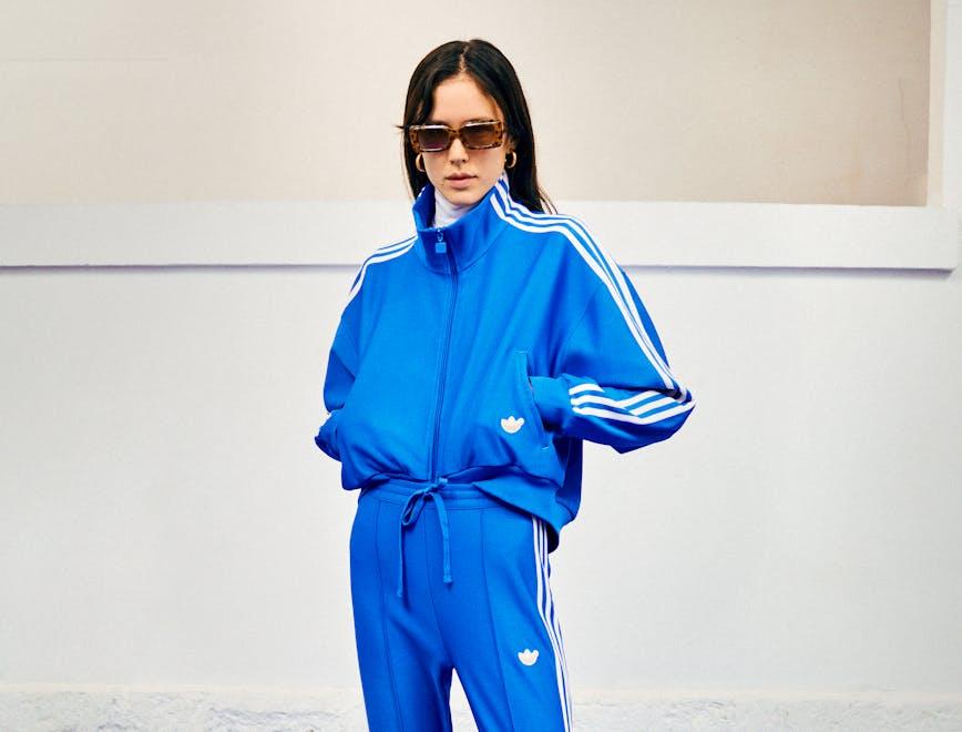 Modella indossa la tuta blu di adidas Originals Blue Version con pantaloni staffa